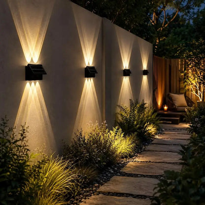 Garden pathway with wall-mounted lights and outdoor seating area at night.
