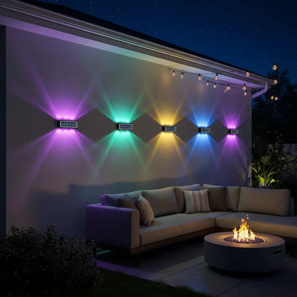 Outdoor setting with colorful wall lights and a fire pit at night.