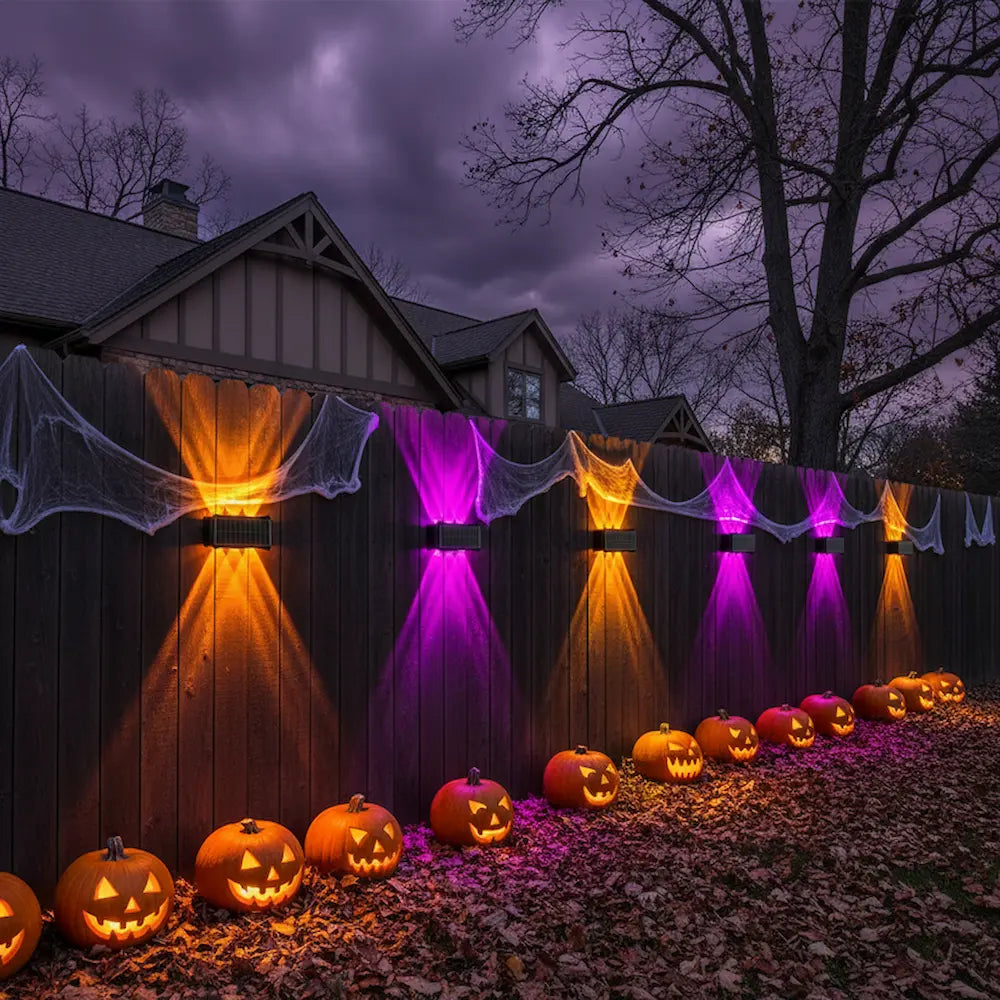 Halloween decorations with illuminated pumpkins and colorful lights on a wooden fence.