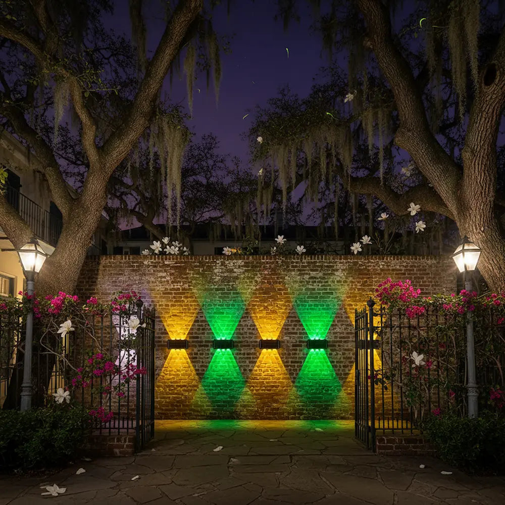 Brick wall with geometric lighting design at night, surrounded by trees and flowers.