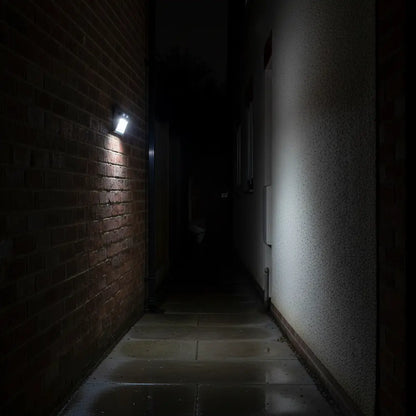 Dark alleyway with a light fixture on a brick wall
