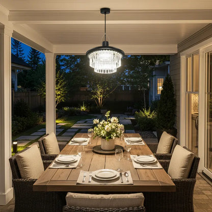 Dining table set for four with a chandelier above, in an outdoor patio setting.