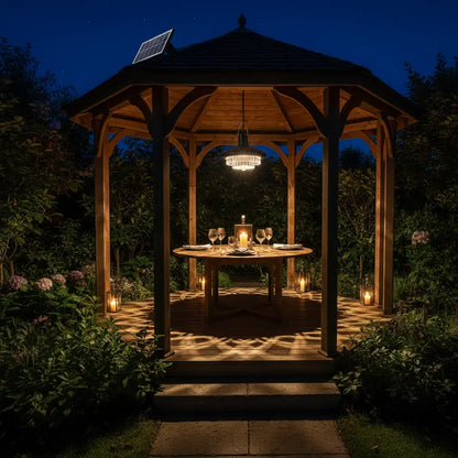 Wooden gazebo with a table set for dinner in a garden at night.