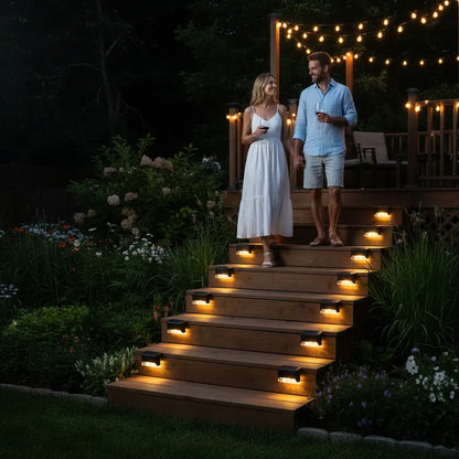 Couple walking up a set of outdoor stairs illuminated by string lights at night.