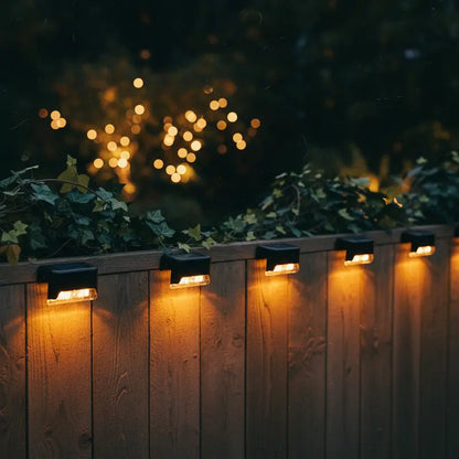 Outdoor lighting fixtures on a wooden fence with a blurred bokeh effect in the background.
