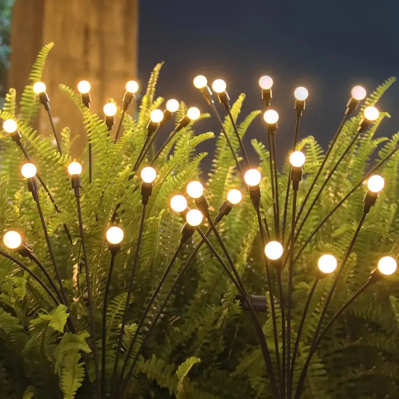 Decorative outdoor light fixture with illuminated bulbs on a plant against a dark sky.