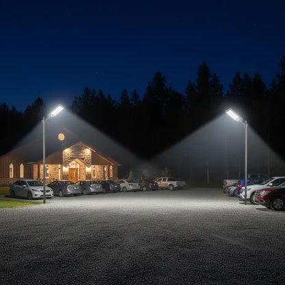 Parking lot with cars and a building at night under streetlights.