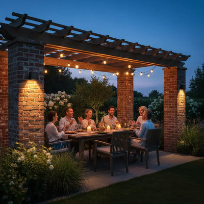 People dining under a pergola with string lights and brick columns at dusk.