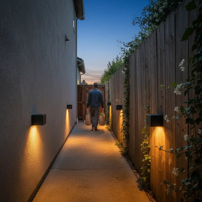 Person walking down a dimly lit pathway with wall lights on either side.