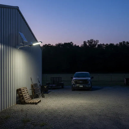 Truck parked outside a building with a solar panel on the roof at night.