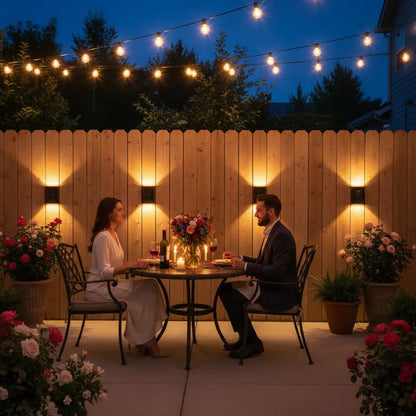 Couple dining outdoors at night with string lights and flowers.