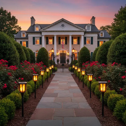 Stately mansion with a well-manicured garden and pathway at dusk.