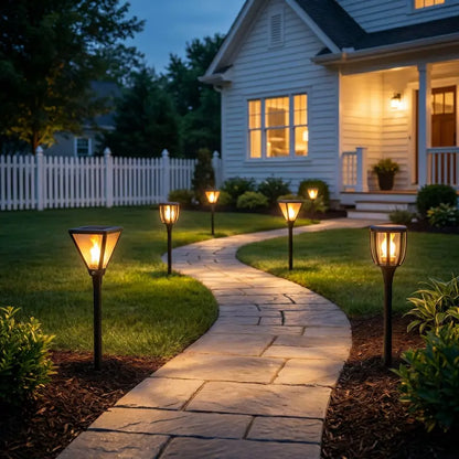 Pathway leading to a house with illuminated solar lights on either side.