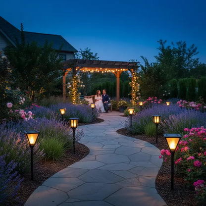 Garden pathway with decorative lights, flowers, and a couple sitting under a wooden pergola at dusk.