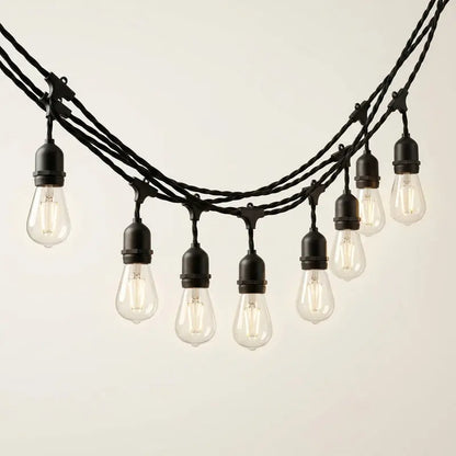 String of vintage-style light bulbs with black wire on a neutral background