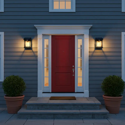 Front door of a house with a red door and white trim, flanked by two potted plants.